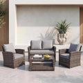 4 seater rattan garden sofa set with cushioned two-seater sofa, armchairs, and glass-top coffee table in modern outdoor patio setting